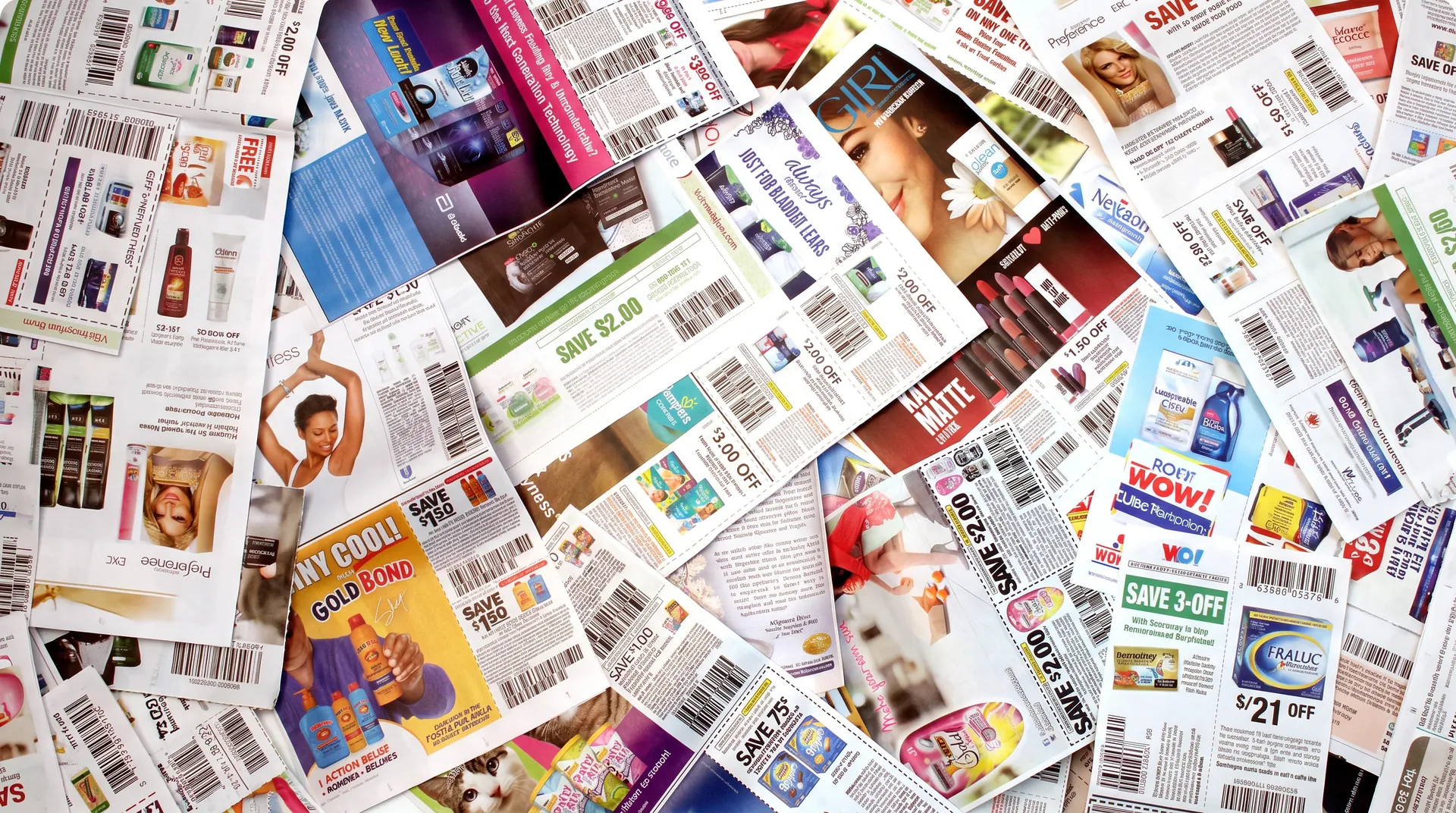 Assorted printed retail coupons spread across a surface.